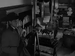 Steed takes cover in the shadows of the library, atop a ladder when robertson enters and signals the Last Post on his bugle